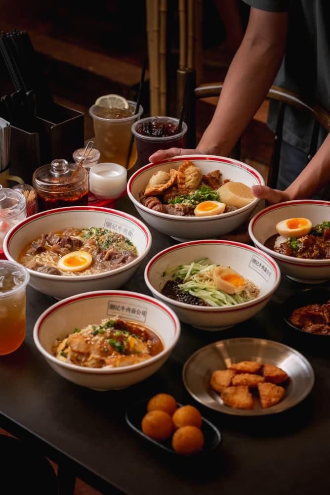 Teowkee table spread — staff serving multiple bowls of noodles and rice dishes