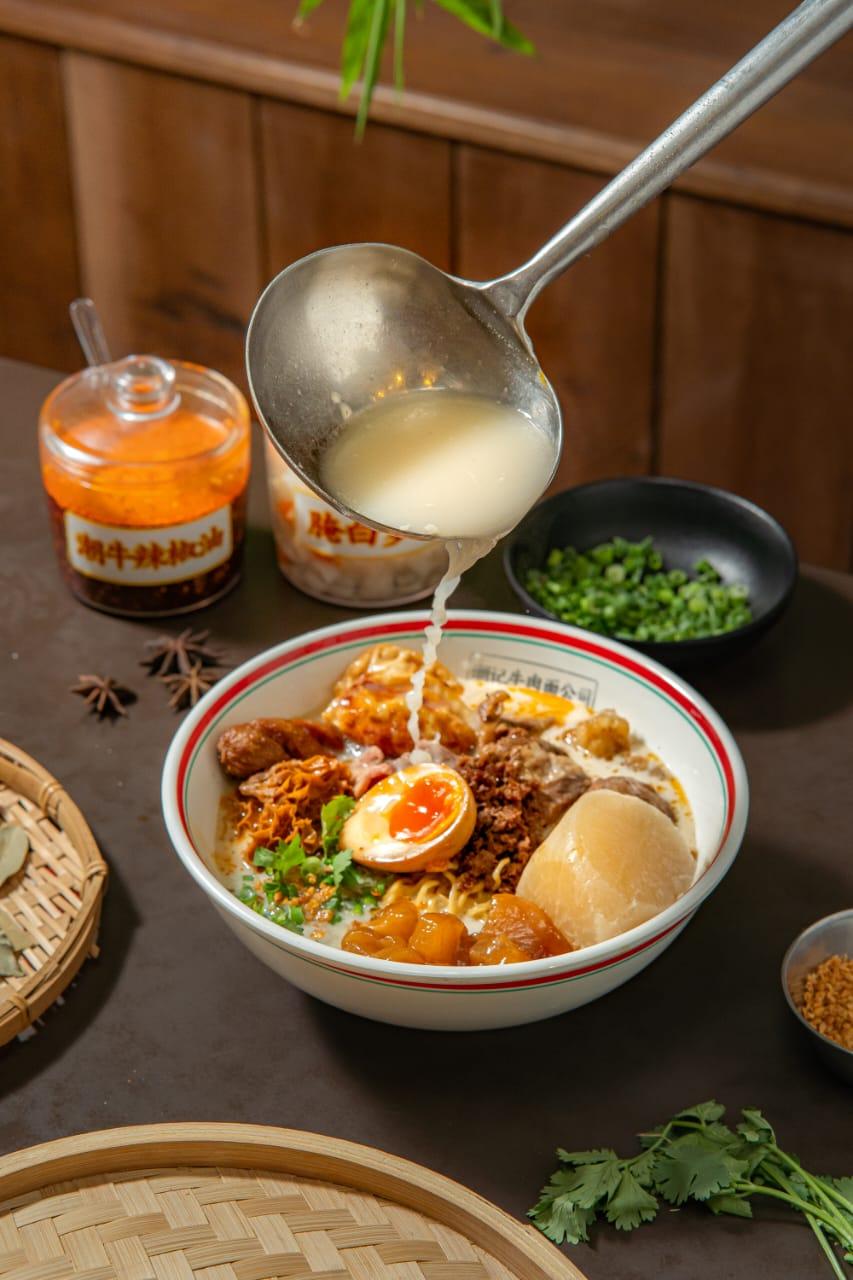 Milky beef broth being ladled into a Teowkee bowl